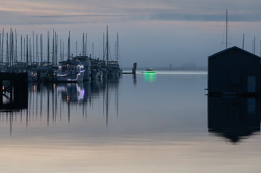 Small boat moves across the harbor on a foggy winter afternoon in Everett WA USA