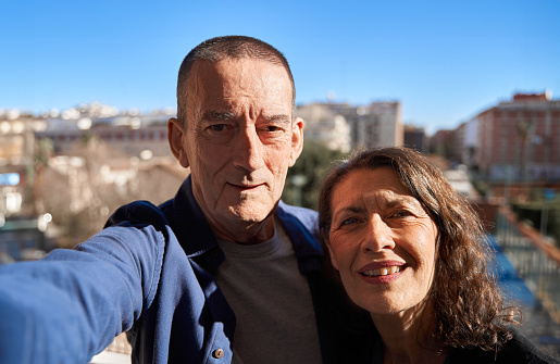 Mature senior couple happy while smiling taking selfie with smartphone on rooftop