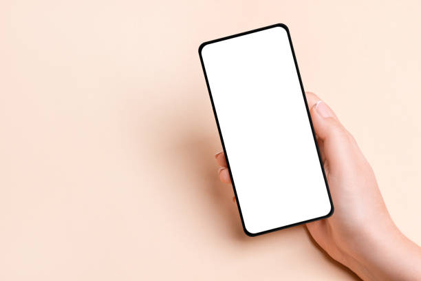 istock Female hand holding a phone with a blank screen on a beige background 1930372800