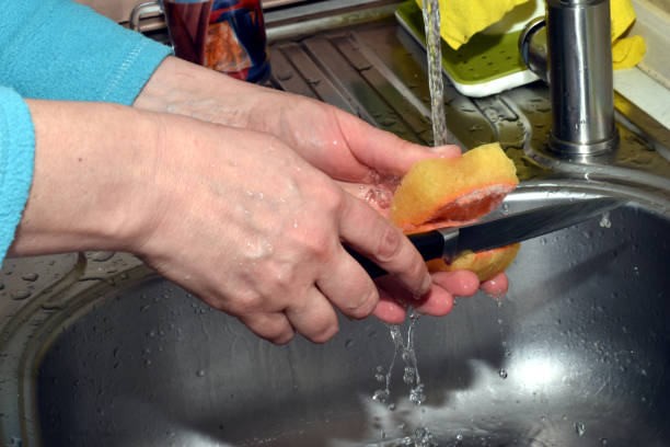a woman washes a knife with a sponge. - sink domestic kitchen kitchen sink faucet imagens e fotografias de stock