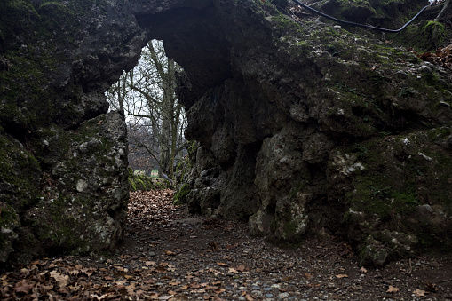 Passage under a rock formation in a park on a cloudy day in autumn