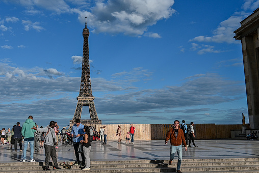 Paris,France,July 1,2022. The Eiffel Tower seen from the square of the TrocadÃ©ro monumental area. People and souvenir sellers characterize the place. Travel destinations.