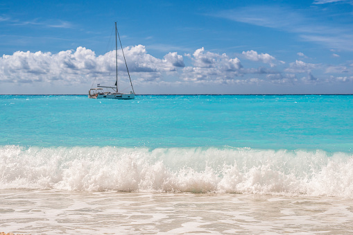 Sumer sea scenery at beach with clouds, dramatic sky, waves, sand, turquoise water and boating at the sea