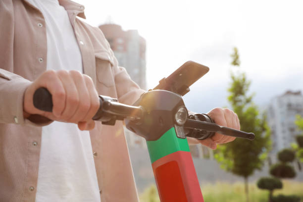 istock Man riding modern electric kick scooter with smartphone outdoors, closeup 1930473138