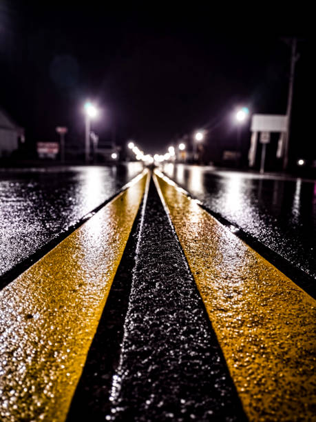 Expressway curved entrance ramp road traffic arrow signs are illuminated by car headlights at night.