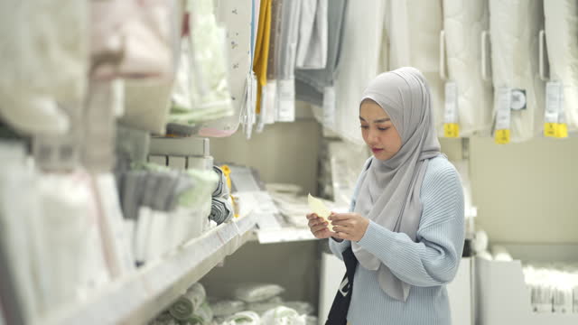 4K Young Muslim Woman Checking A Shopping List On Paper And Choosing Produce In A Shopping Mall