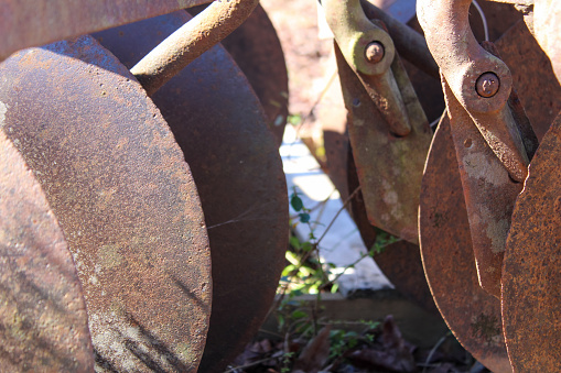 part of an old round rusty iron brown circular saw on a metal table in a workshop