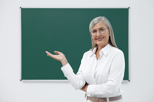 Portrait of happy professor near blackboard in classroom