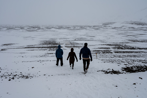 Three hikers on snow-covered trail to Askja Crater in Vatnajokull National Park in northern Icelandic highlands.