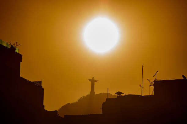 sun setting with Christ the Redeemer in Rio de Janeiro, Brazil - July 6, 2023: Sunset with the statue of Christ the Redeemer seen from the Copacabana neighborhood in Rio de Janeiro.