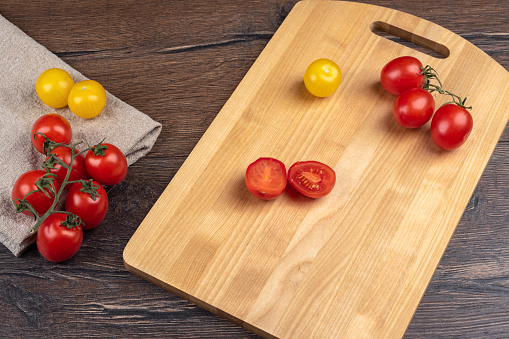 Ripe tomatoes on a cutting board and rough cloth over a wooden background. Healthy eating.