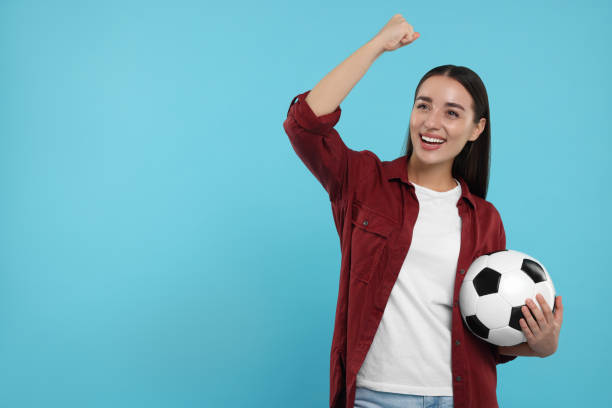 istock Happy fan holding soccer ball and celebrating on light blue background, space for text 1930590913