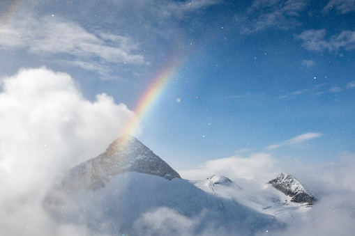 Magical weather in the high mountains with snow, sun, blue sky, clouds, snow crystals and a rainbow. Hintertux Glacier in Austria1,500-3,250 meters. Skiing is possible 365 days all year round.