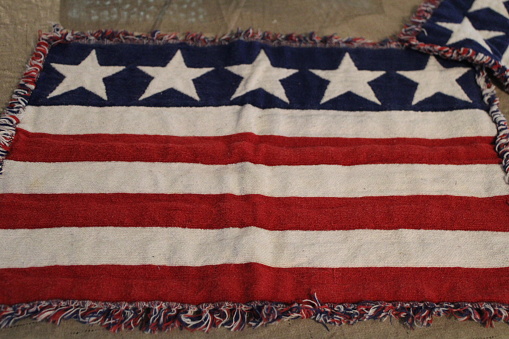 A team of US Navy personnel holding an outstretched American Flag at a Military burial of a US Naval Officer. Headstones out of focus in background. Selective focus on front edge of the flag.