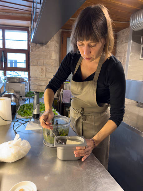 istock Professional female chef preparing food in modern restaurant kitchen. He makes appetizers with vegetables in the blender. 1930670591
