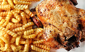 Whole grilled chicken and fries on ceramic plate