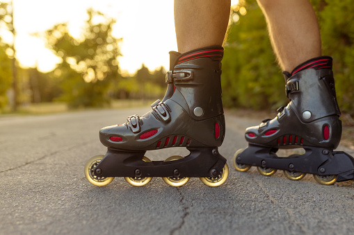 unrecognizable feet with rolling skate close up on rural paved street with sun flare or back light low angle view.
