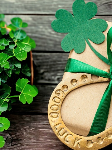 Clover leaves and horseshoe on wooden table, flat lay. St. Patrick's Day celebration
