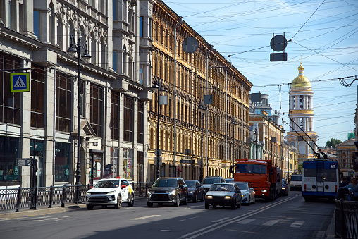 Cityscape of the street, old residential buildings and road with cars in the historical center of St. Petersburg, Russia. Unrecognizable people on the sidewalk, summer sunny day