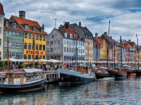 Boats and shops line the historic scenic tourist destination of the Nyhavn canal in the city center of Copenhagen, Denmark.