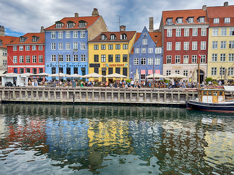 Reflections from the buildings at the Nyhavn promenade in Copenhagen highlight the crowded promenade.