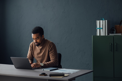 An office scene showing a professional at his desk, using a laptop for various business activities and strategies.