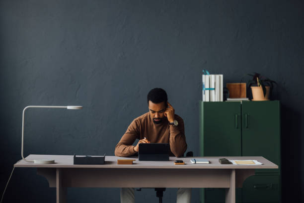 istock Young Businessman Sitting at His Desk and Using Tablet in Office 1930804539