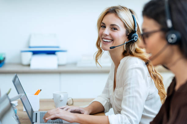 istock Successful attractive businesswomen working with laptops while talking with earphone on coworking place. 1930812838