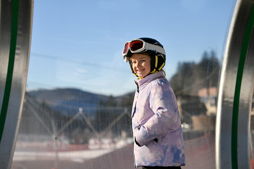 A girl on skis stands on a carpet ski lift in a tunel