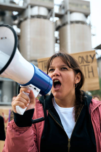 istock Angry and rebellious woman speaking and protesting with megaphone at demonstration at climate change 1930833095
