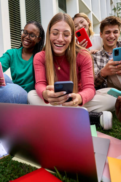 group of young multiracial university students immersed on their mobile cell technology addicted - multi ethnic group concentration mobile phone using laptop imagens e fotografias de stock