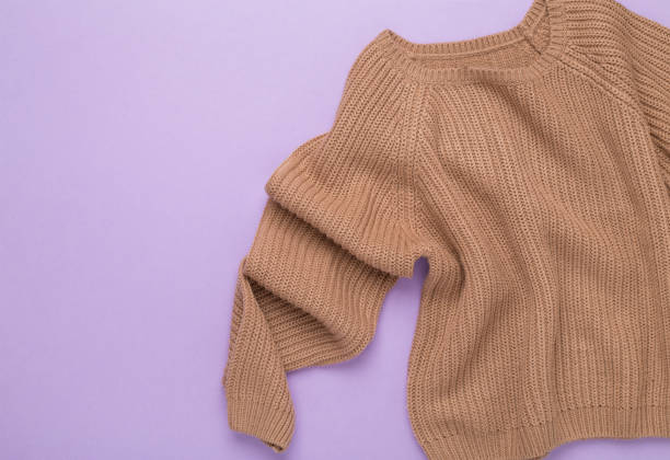 istock Beige knitted sweater on color background, top view 1930874060