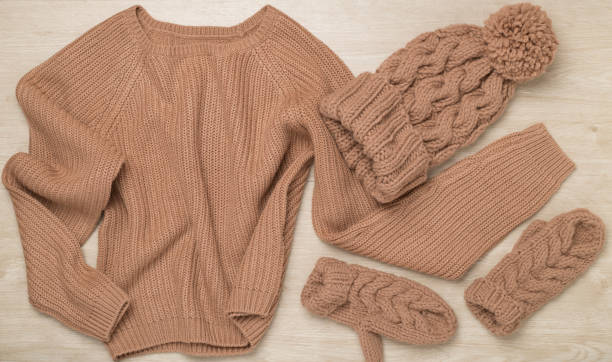 istock Sweater and winter hat with mittens on wooden background, top view. 1930874061