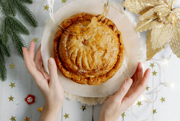 istock A woman's hands clasp a box with a royal galette and a crown on the table. 1930909601