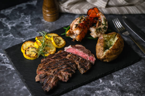 surf and turf, ribeye steak and lobster tail on black marble background - surf and turf prepared shrimp steak grilled ストックフォトと画像