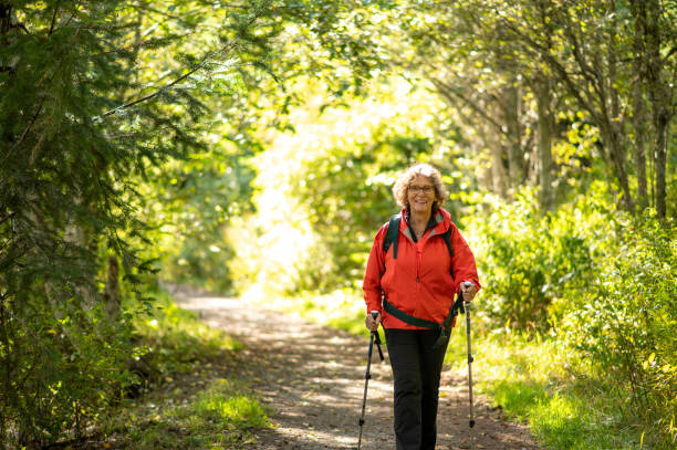 Senior woman hikes through forest Senior woman hikes through forest on sunny day pacific northwest region stock pictures, royalty-free photos & images