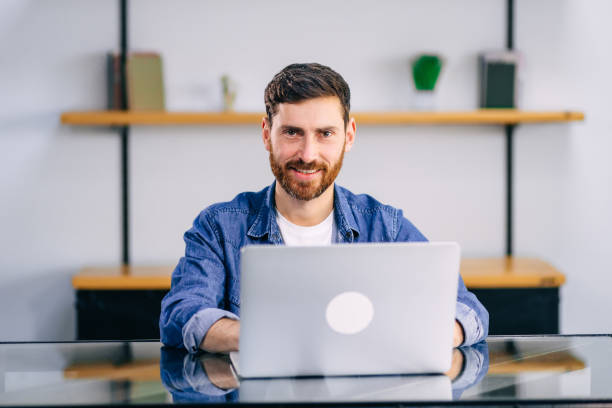 istock Smiling young man working on laptop in modern kitchen, checking email in morning, writing message in social network, happy young male using internet banking service, searching information 1930972289