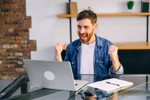 istock A cheerful young bearded man in a light shirt is sitting at the 1930972299