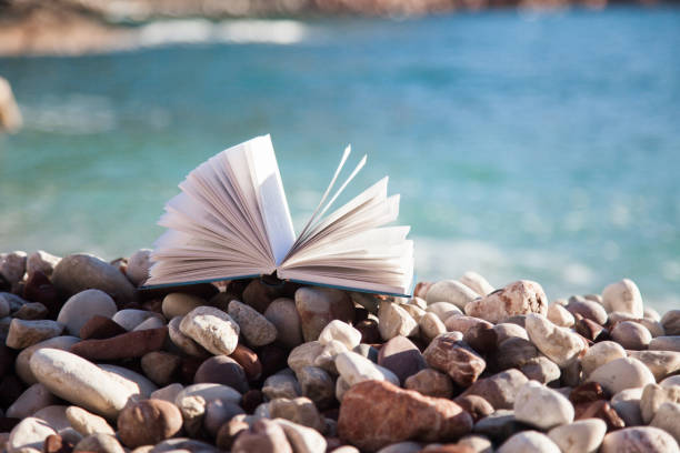 istock Open book on beach by blue and aquamarine sea. 1930973482