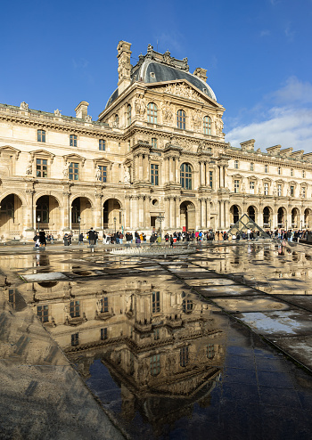 France, Paris - Jan 03, 2024 - View of The historical palace building with water reflection effect by after raining at the Louvre museum in Paris. is one of the world's largest museums in Paris, Space for text, Selective focus.