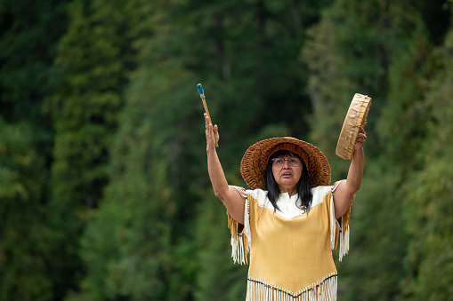Portrait of indigenous woman with drum in forest