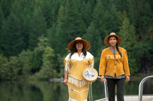 Indigenous women stand on lake pier together