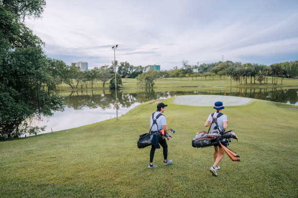 Asian male golfer walking toward putting green in golf course weekend morning