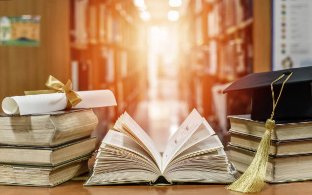 Book in library for education learning concept with open old textbook, stack piles of literature text archive on reading desk, and blur aisle of bookshelves in school study class room background libro en la biblioteca para el concepto de aprendizaje de la educación con un libro de texto viejo abierto, pila de archivos de texto de literatura en el escritorio de lectura y pasillo borroso de estanterías en el fondo de la sala de clases de estudio d