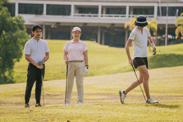 Asian chinese female golfer teeing off while friends watching in golf course weekend morning