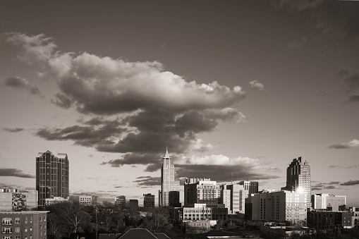 A sunset skyline of downtown Raleigh North Carolina with a dramatic cloudy sky in monochrome.