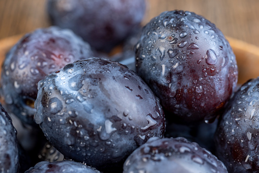 Wet purple plum on the table, delicious fresh harvest of oval-shaped and purple-colored plums in drops of water