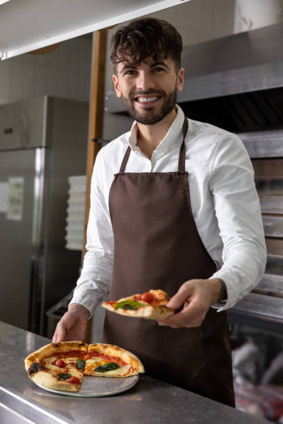 istock Smiling dark-haired pizzeria worker with pizza slice in hands 1931089728