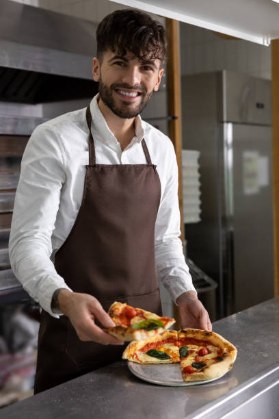 istock Smiling dark-haired pizzeria worker with pizza slice in hands 1931089729
