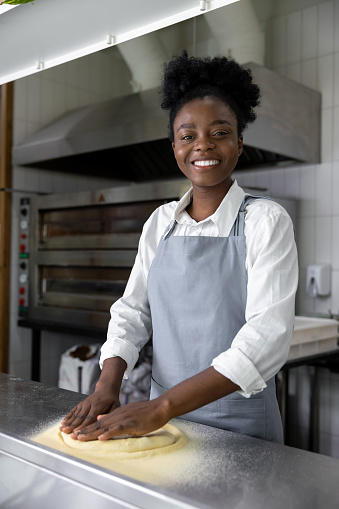 Dark-skinned woman in pizzeria cooking pizza